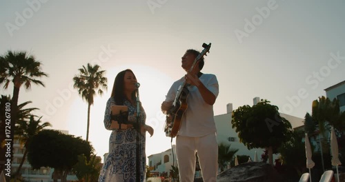 Couple performing music at sunset in tropical resort setting