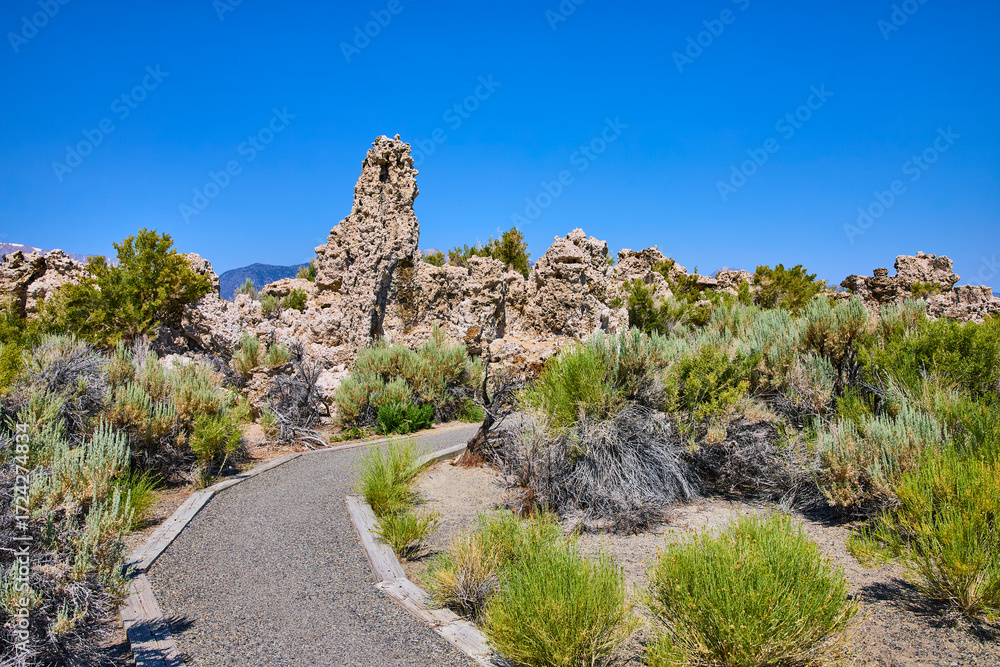 Obraz premium Tufa Formations and Walking Path with Native Brush Under Blue Sky
