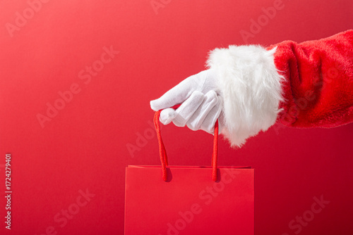 Wallpaper Mural Santa Claus hand holding shopping bag with copy space on red background, Christmas shopping concept. Torontodigital.ca