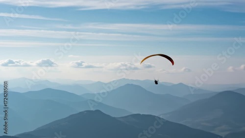 Paraglider flying over mountains and clouds