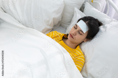 Foto Young women with fever patch sleeping in bed, recovering from flu or illness