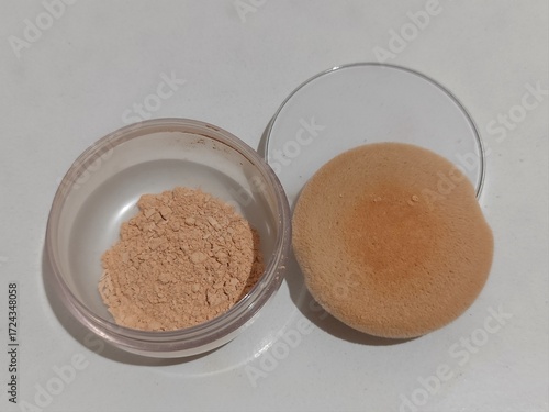 Cosmetic loose face powder with sponge puff on a white background. Perfect for beauty, makeup, and skincare concepts