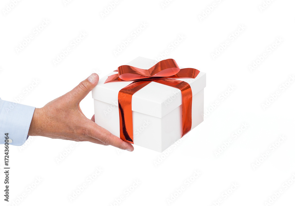 Fototapeta premium Hand holding white gift box with glossy red ribbon and bow in plain white studio
