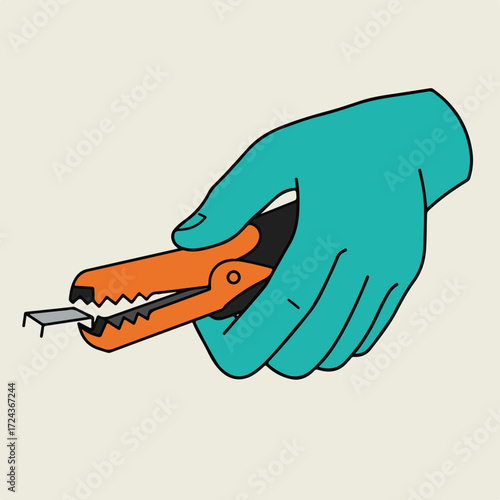 Turquoise hand holds orange staple remover extracting a grey staple, cream background
