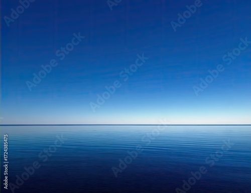 Tranquil expanse of a vast, serene blue ocean meeting a cloudless blue sky