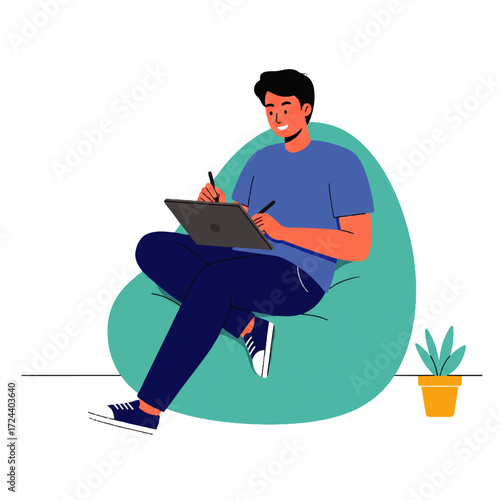 A young man sits comfortably in a beanbag chair, using a stylus on a tablet, with a small potted plant nearby.