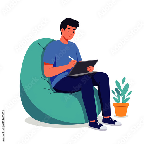 A young man sits comfortably on a beanbag chair, using a stylus and tablet to draw or design, with a potted plant nearby.