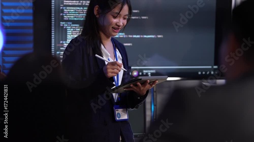 A female tech lead or scrum master leads a sprint planning meeting, explaining the codebase on a large screen and outlining new features for her development team in an agile company.