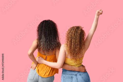 Young women hugging on pink...