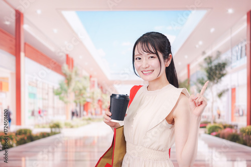 コーヒーを飲みながらショッピングモールで買い物をする女性