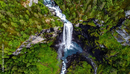 Waterfall cascading down rocky cliffs, surrounded by lush greenery