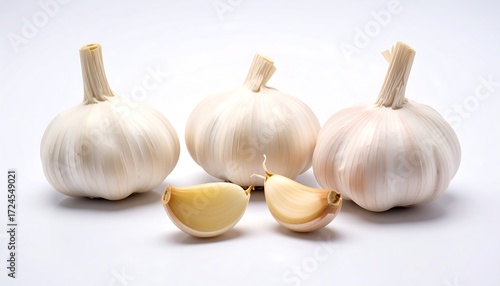 Three whole heads of garlic, with a clove split in half, displayed on a plain white background