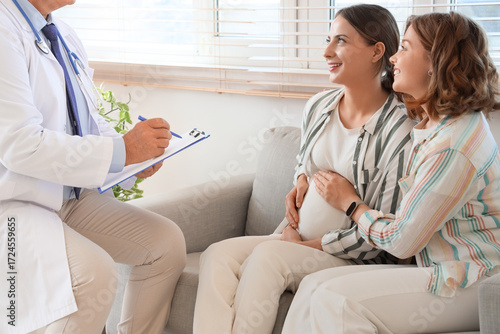Young pregnant lesbian couple visiting fertility doctor after IVF in clinic