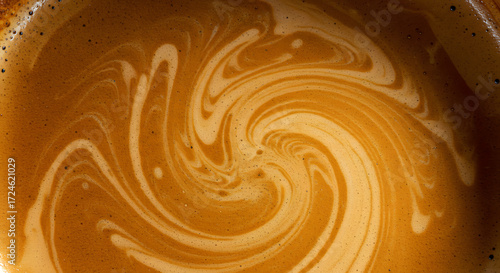 A captivating close-up reveals the swirling, creamy surface of a rich brown liquid, creating a mesmerizing abstract design of light and shadow, evoking feelings of warmth, comfort, and indulgence