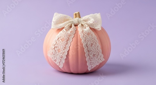 Elegant pink pumpkin adorned with a delicate lace bow on purple backdrop