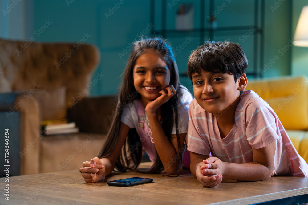 Fototapeta premium Indian Asian siblings kids using smartphones to play games while enjoying leisure time at home