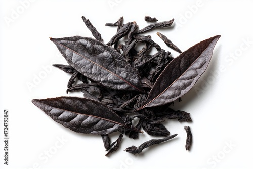 Dark, oxidized tea leaves, some whole, others fragmented, arranged on a stark white background; overhead shot