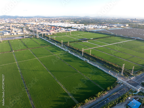 Aerial view of green fields and an industrial area under a clear sky