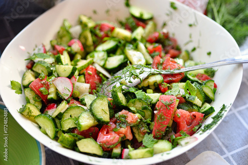Vegetable salad is dressed with olive oil and served in a plate