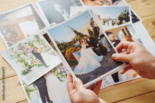 Men's hands put on the wooden table and show wedding photos.