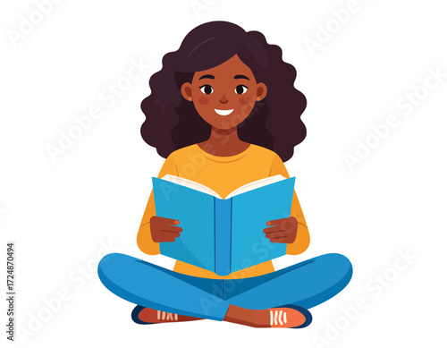 Smiling African American woman reads a blue textbook sitting cross legged on a white background floor.