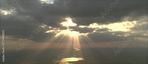 Fototapeta Naklejka Na Ścianę i Meble -  Sunlight breaking through dark clouds over the ocean, creating a dramatic and beautiful scene.