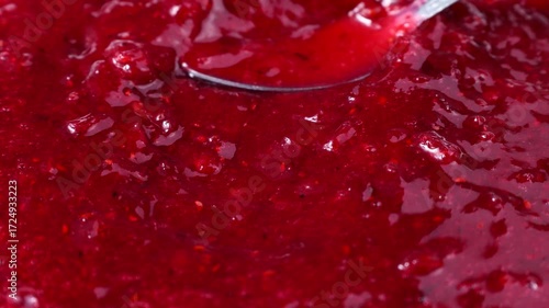 Bright red cranberry sauce spreading with a spoon close up