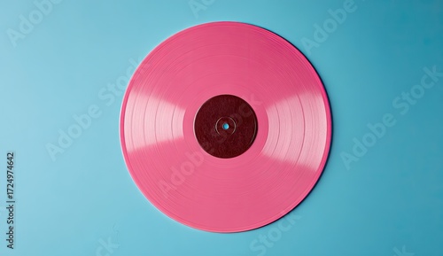 A vibrant pink vinyl record sits on a light blue background, showcasing its glossy surface and concentric grooves.  The central label is a darker maroon