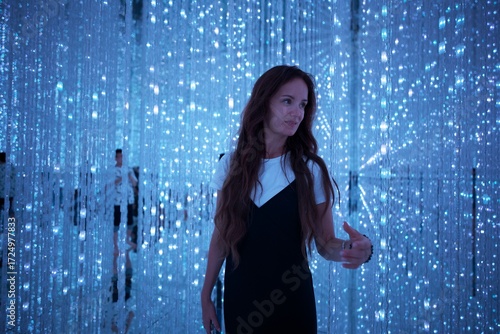 Young woman exploring shimmering blue LED lights in a futuristic immersive atmosphere