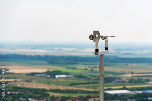 Wallpaper Mural Close-up of an anemometer used for measuring wind speed, positioned on a hilltop with blurred fields and sky in the background Torontodigital.ca