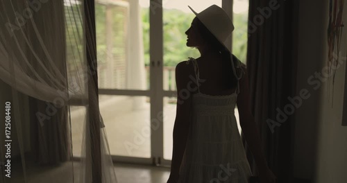 Young Woman Arriving At Tropical Resort Room With Suitcase And Balcony View