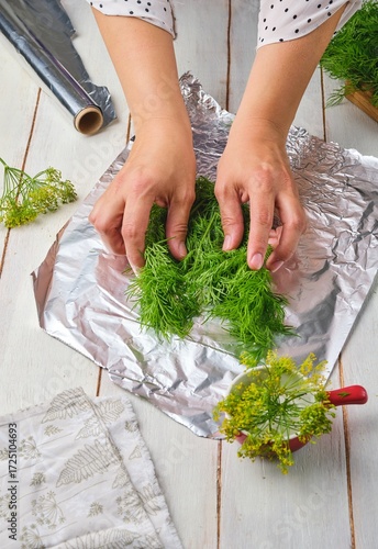 Foto Step-by-step preparation of frozen dill in a foil wrapper for freezer storage on a light wooden background