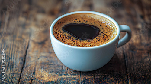 Freshly brewed coffee served in a white cup on a rustic wooden table showcasing rich colors and frothy texture, perfect for a morning boost of energy