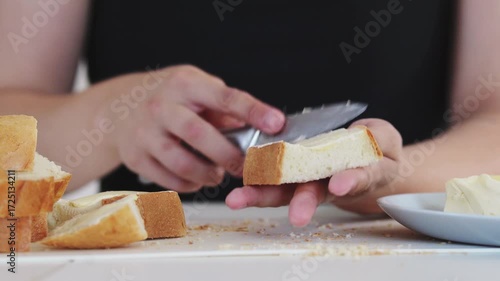 A young woman prepares fresh sandwiches with butter, sausage, and cheese on crispy bread. Close-up shots showcase the appetizing food preparation process in a modern kitchen