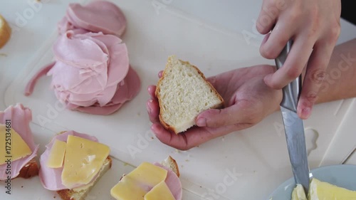 A young woman prepares fresh sandwiches with butter, sausage, and cheese on crispy bread. Close-up shots showcase the appetizing food preparation process in a modern kitchen