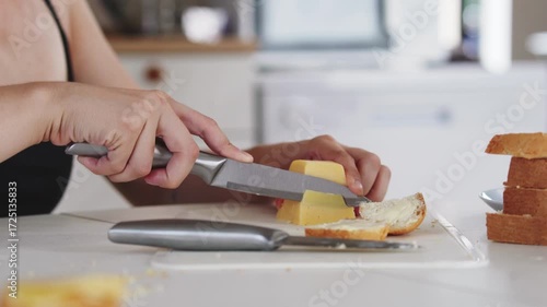 A young woman prepares fresh sandwiches with butter, sausage, and cheese on crispy bread. Close-up shots showcase the appetizing food preparation process in a modern kitchen