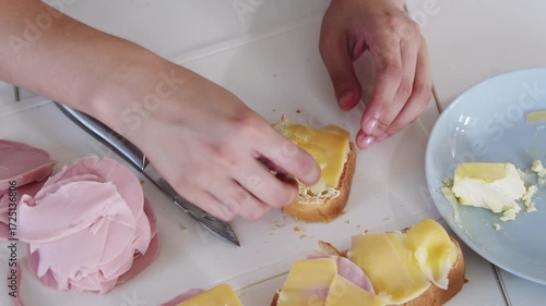 A young woman prepares fresh sandwiches with butter, sausage, and cheese on crispy bread. Close-up shots showcase the appetizing food preparation process in a modern kitchen