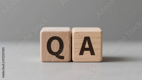 Wooden cubes with letters Q and A arranged on a neutral gray background, symbolizing the concept of questions and answers, support, and information