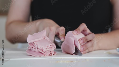 A woman prepares delicious sandwiches with cheese, butter, and sausage in a sunny kitchen. Authentic cooking process showcasing simple, comforting food preparation