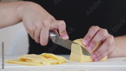 A woman prepares delicious sandwiches with cheese, butter, and sausage in a sunny kitchen. Authentic cooking process showcasing simple, comforting food preparation