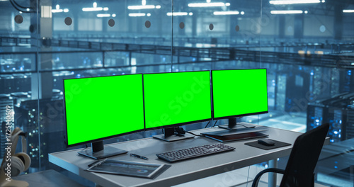 Obraz na plátně Modern Office Desk in a Data Center with Multiple Monitors with Green Screen Mock Up Displays, Ready for a Team of Developers to Dive In