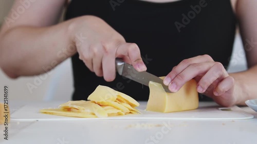 A woman prepares delicious sandwiches with cheese, butter, and sausage in a sunny kitchen. Authentic cooking process showcasing simple, comforting food preparation