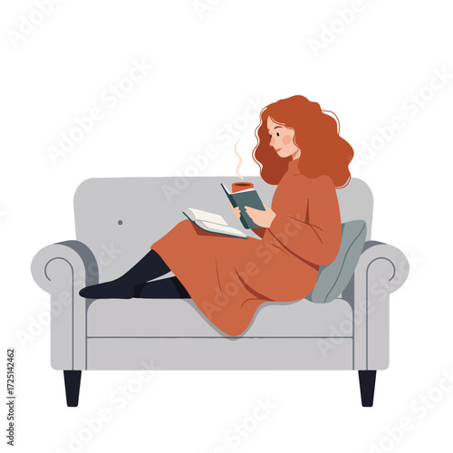 Woman reads book while on grey sofa with coffee