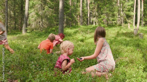 In slow motion, five children collect wild berries in a lush green forest on a sunny summer day, sharing curiosity, teamwork, and nature connection