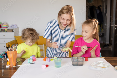 Happy family painting together. Young mother learn her little children to draw. Family art therapy and having fun time at home.