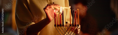 Foto Header of woman lighting candles on menorah during Hanukkah celebration, holding