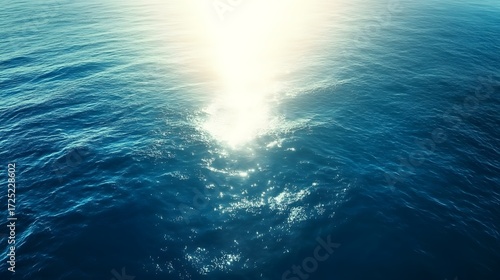 High-angle view of deep blue ocean water reflecting a bright, radiant light source, showcasing the texture of the waves.