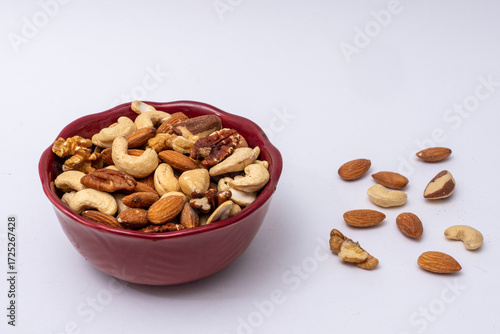 Mixture of different nuts in red bowl on white—healthy snack, vegan protein, natural food concept