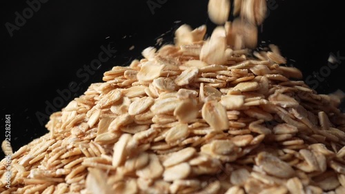 Slow motion close-up of fresh oat grains falling and bouncing on black background. Premium footage ideal for health food commercials, breakfast product ads, and agricultural content.
