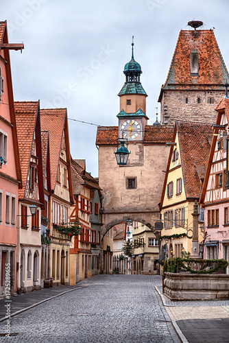 Historic cobblestone street in Rothenburg ob der Tauber, featuring medieval half-timbered houses and clock tower at winter morning, Bavaria, Germany.
